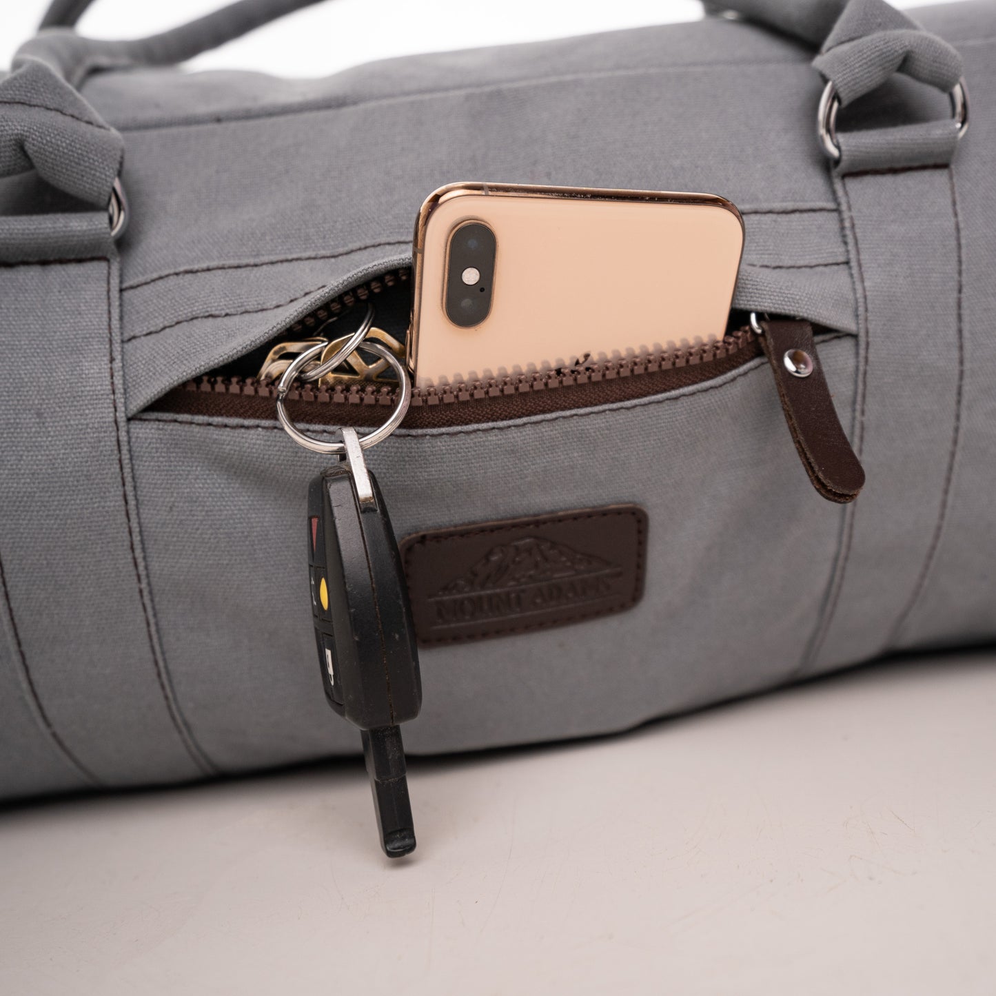 gray duffle bag with exterior pocket for phone and keys